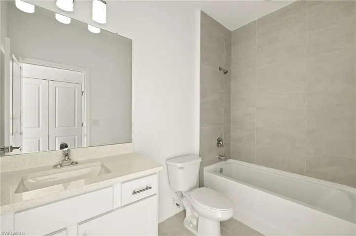 Full bathroom with tile patterned flooring, vanity, toilet, baseboards, and shower / bathing tub combination