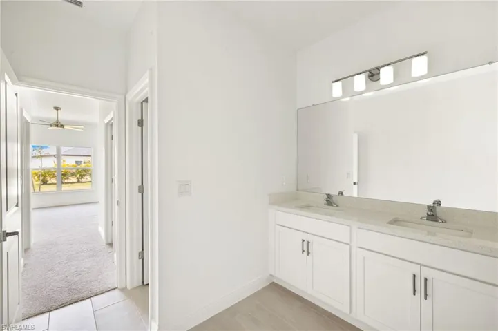 Bathroom with double vanity, a ceiling fan, tile patterned floors, and a sink
