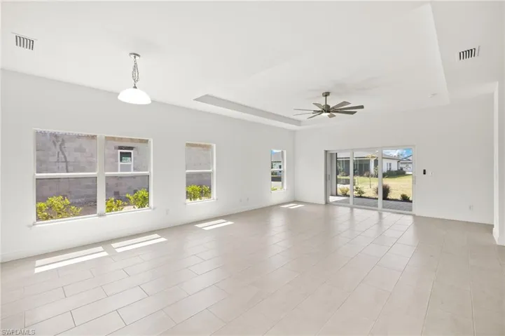Unfurnished room with visible vents, a raised ceiling, ceiling fan, and baseboards