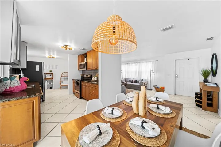 Dining area featuring a wood-finish table, overhead woven pendant light fixture, and tile flooring