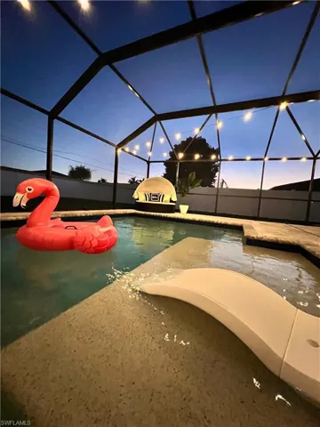 Screened pool enclosure featuring a pool with a built-in water feature and string lights