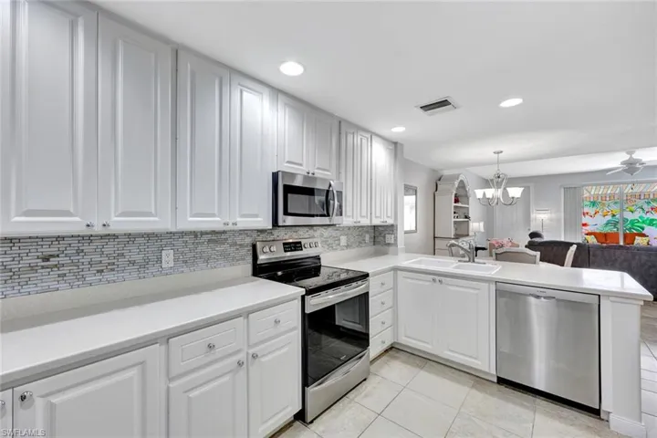 Kitchen features white cabinets and stainless appliances.