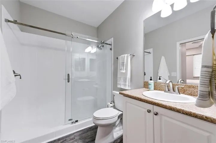Bathroom with an enclosed shower, hardwood / wood-style flooring, vanity, and toilet