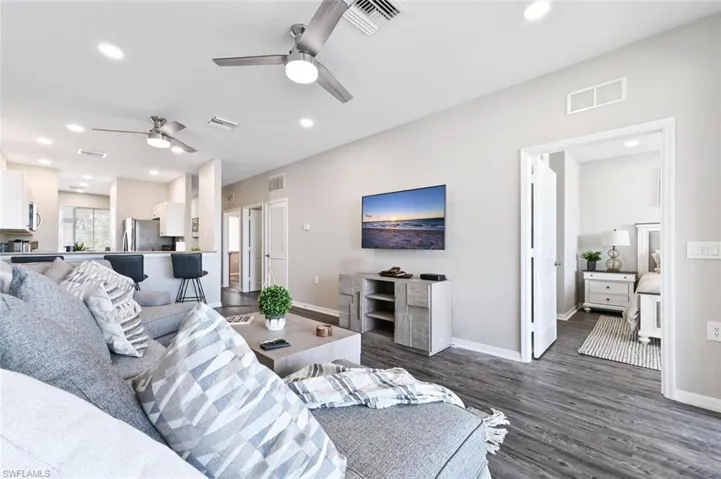 Living room with ceiling fan and dark wood-type flooring
