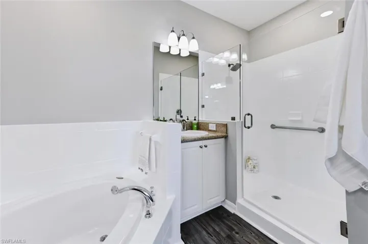 Bathroom with wood-type flooring, vanity, and separate shower and tub