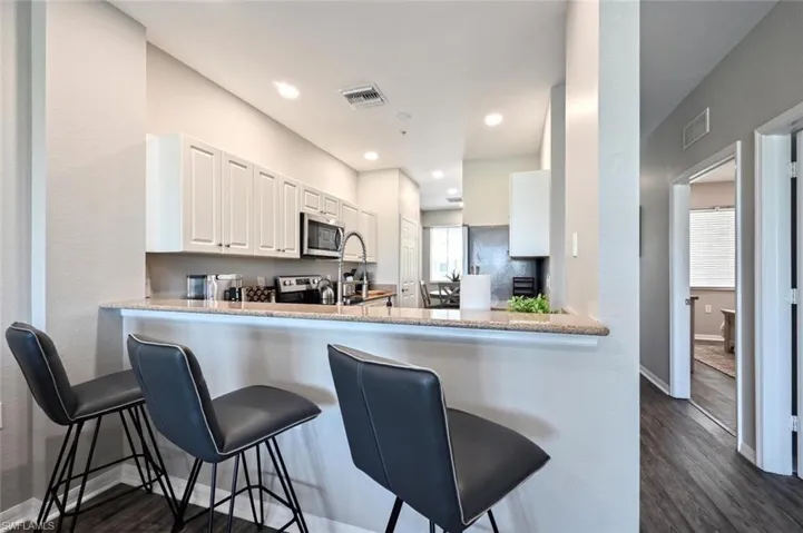 Kitchen featuring white cabinets, appliances with stainless steel finishes, kitchen peninsula, and dark hardwood / wood-style flooring