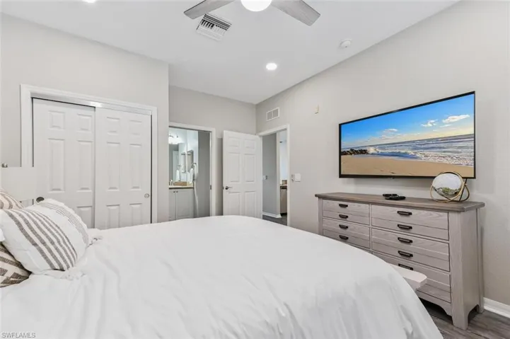 Bedroom with dark hardwood / wood-style flooring, ceiling fan, and a closet