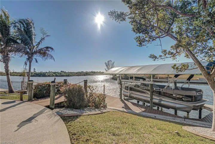 Dock area featuring boat lift, a water view, and a yard