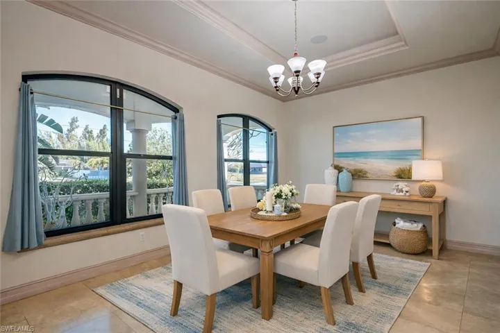 Dining space with ornamental molding, hanging lights, and a raised ceiling