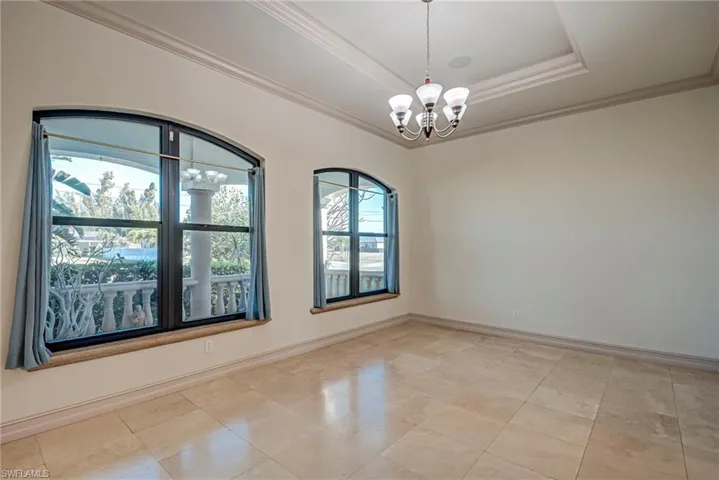 Spare room with a chandelier, crown molding, and a raised ceiling