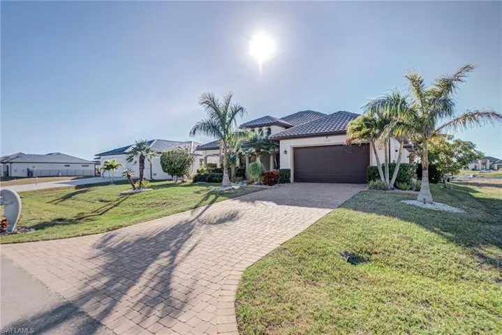 View of front facade featuring a front lawn, decorative driveway, an attached garage, stucco siding, and a residential view