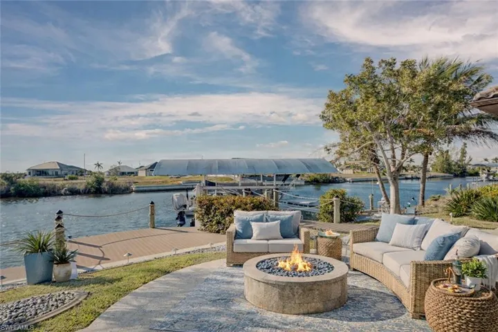 View of patio with a fire pit, a water view, and a boat dock