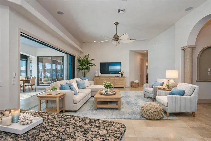 Living room featuring ceiling fan, arched walkways, and light tile patterned floors