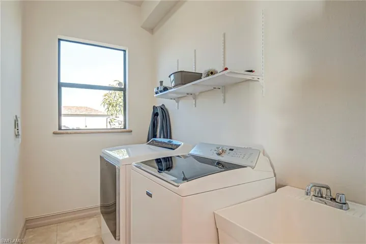 Laundry room featuring washing machine and clothes dryer and light tile patterned flooring