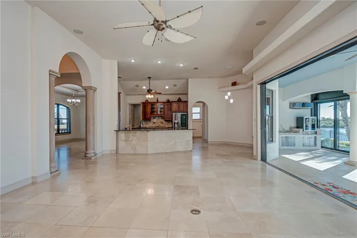 Unfurnished living room with a ceiling fan, arched walkways, decorative columns, and recessed lighting