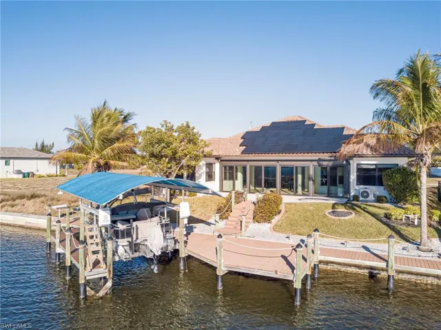 Dock with boat lift, a sunroom, a water view, and a patio area