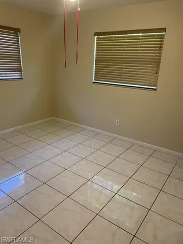 Unfurnished room featuring light tile patterned floors and baseboards