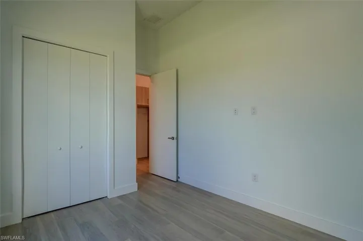 Unfurnished bedroom with light hardwood / wood-style floors, a closet, and a high ceiling