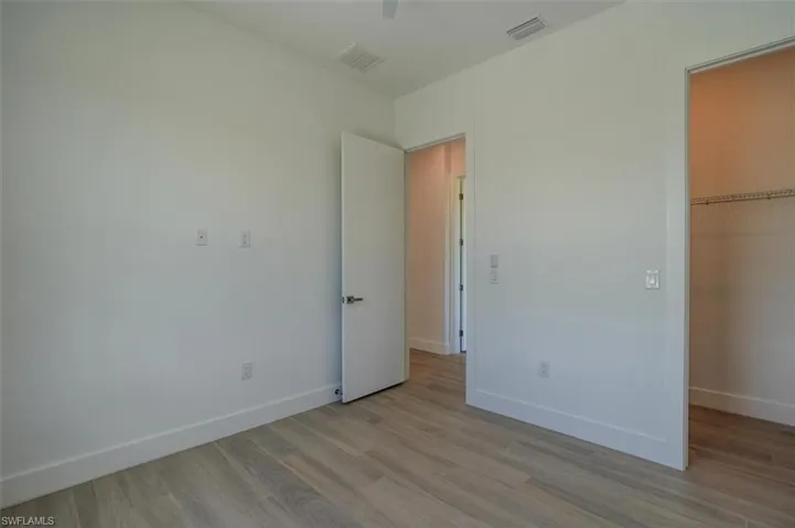 Unfurnished bedroom featuring a closet, a spacious closet, and hardwood / wood-style flooring