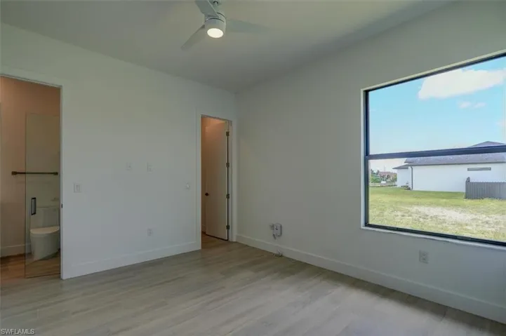 Unfurnished bedroom with light hardwood / wood-style flooring, connected bathroom, and ceiling fan