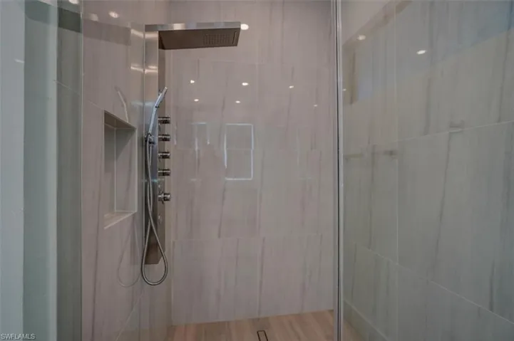Bathroom featuring tiled shower, hardwood / wood-style floors, and tile walls