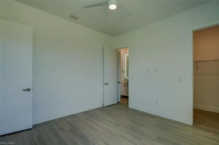 Unfurnished bedroom with a spacious closet, light wood-type flooring, ceiling fan, and a closet