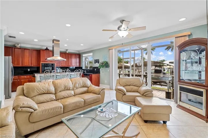 Living room with ceiling fan, ornamental molding, recessed lighting, and light tile patterned flooring