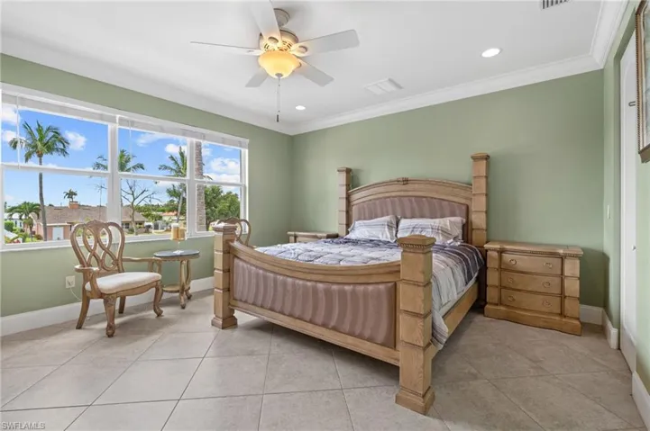 Bedroom featuring ceiling fan, crown molding, and light tile patterned flooring