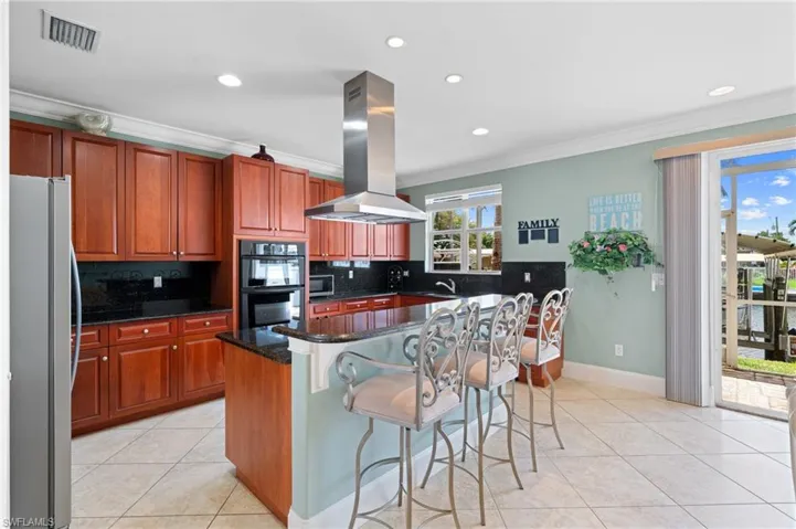 Kitchen with ornamental molding, island range hood, and multiple ovens