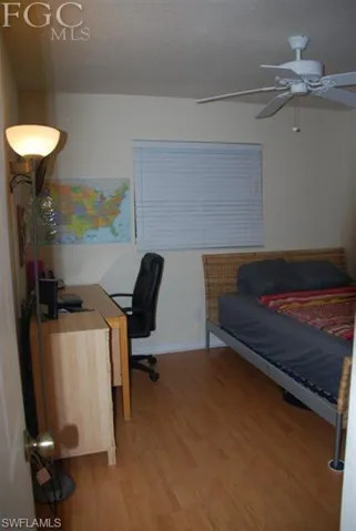 Third bedroom with wood plank flooring, window treatment, ceiling fan