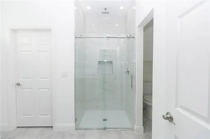 Bathroom with toilet, tile patterned flooring, and an enclosed shower