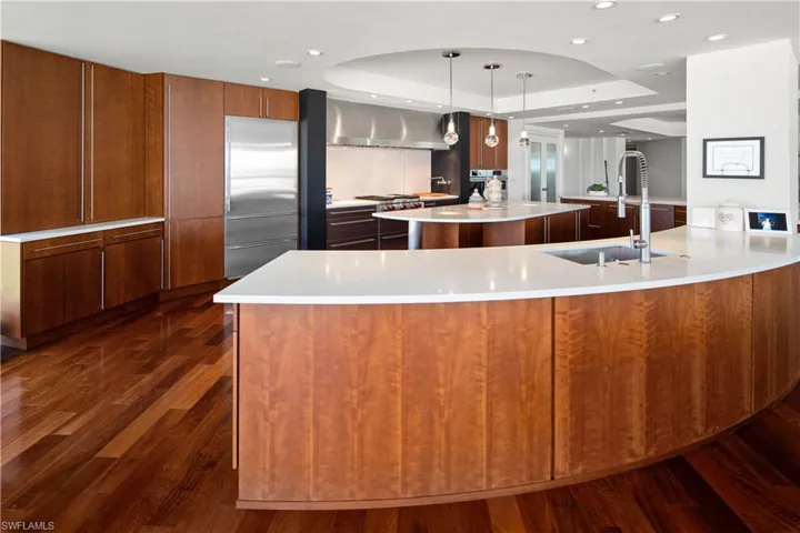Kitchen featuring hanging light fixtures, sink, a tray ceiling, and a large island
