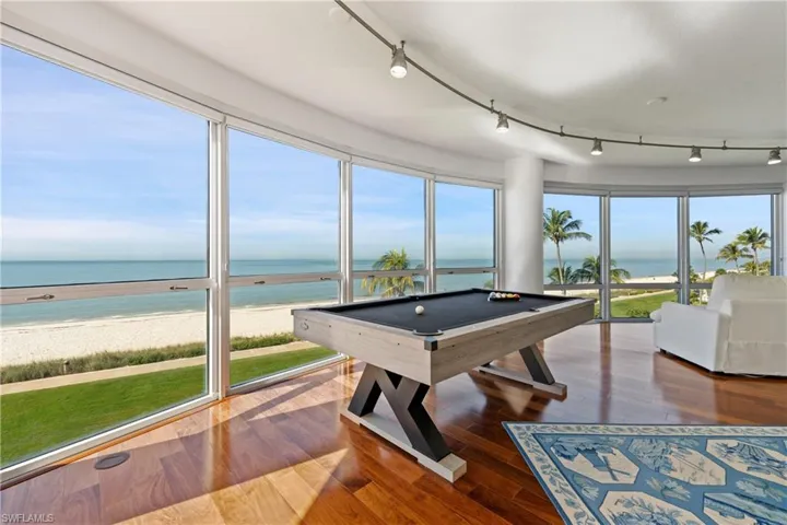 Game room with view of water and beach, billiards table, hardwood / wood-style floors, and track lighting