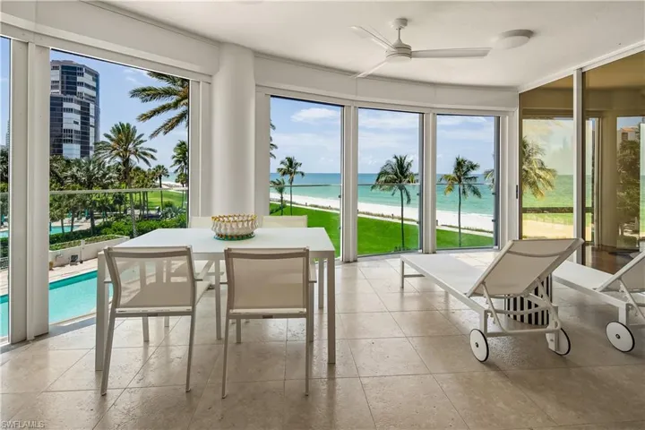 Sunroom / solarium with ceiling fan and a water view