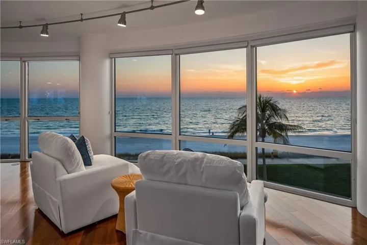 Living room featuring track lighting, a water view, and dark hardwood / wood-style floors