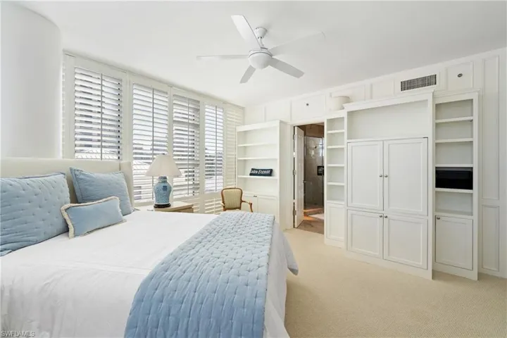 Bedroom featuring ensuite bath, light carpet, and a ceiling fan