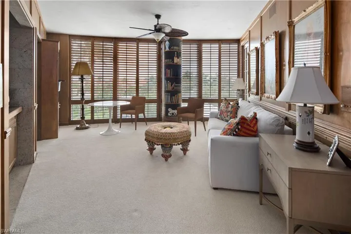 Carpeted living room featuring floor to ceiling windows and ceiling fan