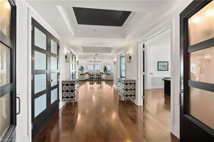 Hallway featuring dark hardwood / wood-style floors, a tray ceiling, and french doors