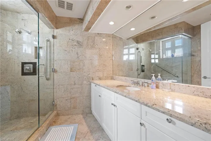 Bathroom featuring vanity, tile walls, a stall shower, recessed lighting, and lofted ceiling