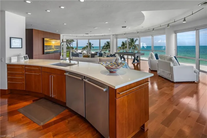 Kitchen featuring a water view, dishwasher, wood-type flooring, track lighting, and sink
