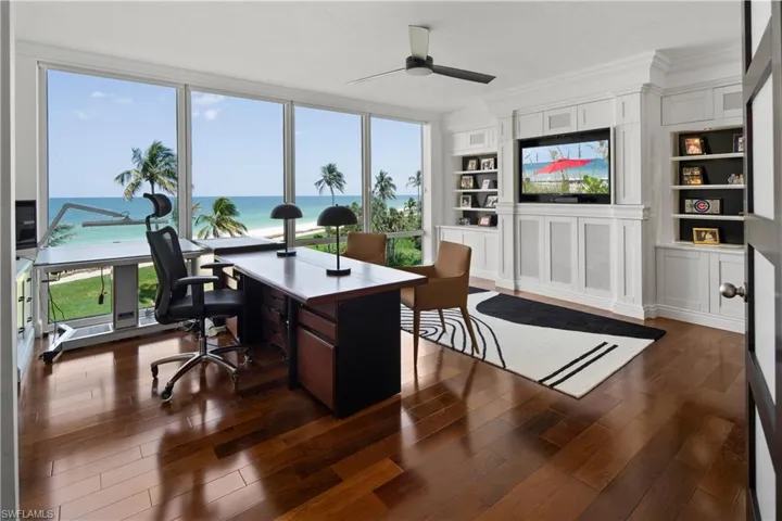 Office area featuring a wealth of natural light, dark wood-type flooring, and a water view