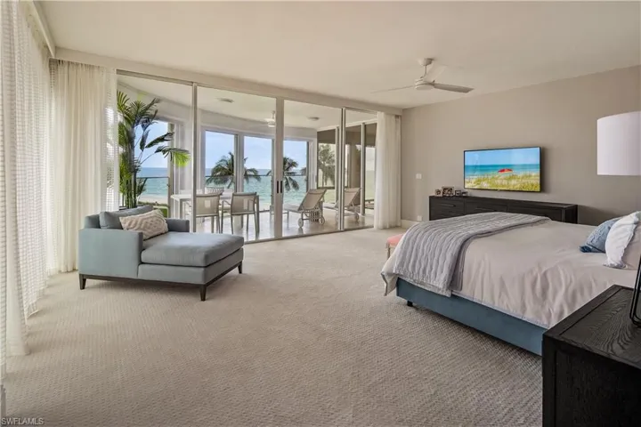 Bedroom featuring ceiling fan, carpet floors, a water view, a wall of windows, and access to exterior