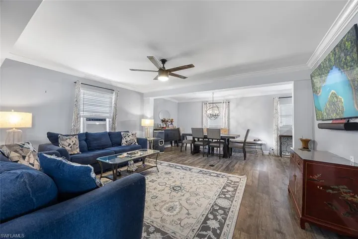 Living room featuring crown molding, vinyl floors, and a healthy amount of natural light
