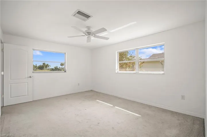 Empty room featuring baseboards, visible vents, ceiling fan, and carpet floors