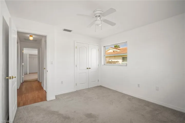 Unfurnished bedroom featuring a closet, ceiling fan, visible vents, baseboards, and carpet floors