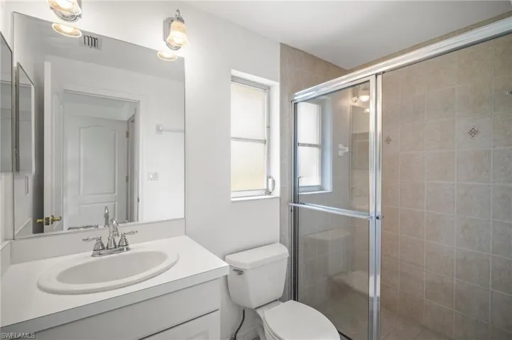 Bathroom with toilet, a stall shower, visible vents, and vanity