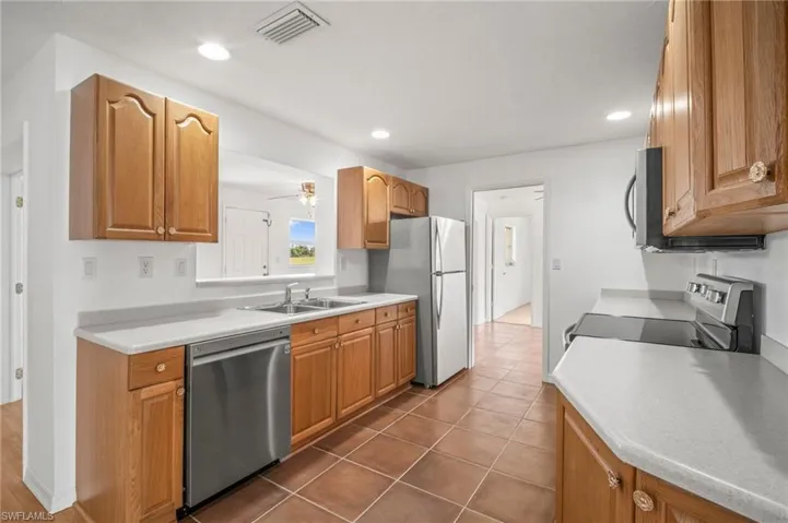 Kitchen featuring brown cabinets, appliances with stainless steel finishes, light countertops, and a sink