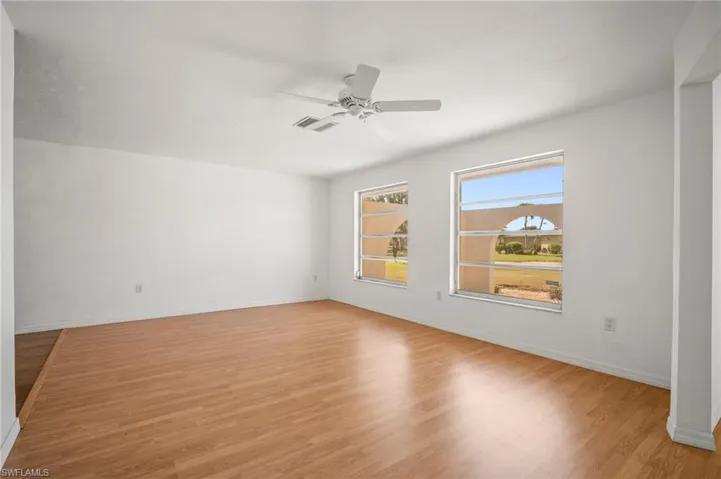 Empty room with baseboards, visible vents, ceiling fan, and light wood-style floors
