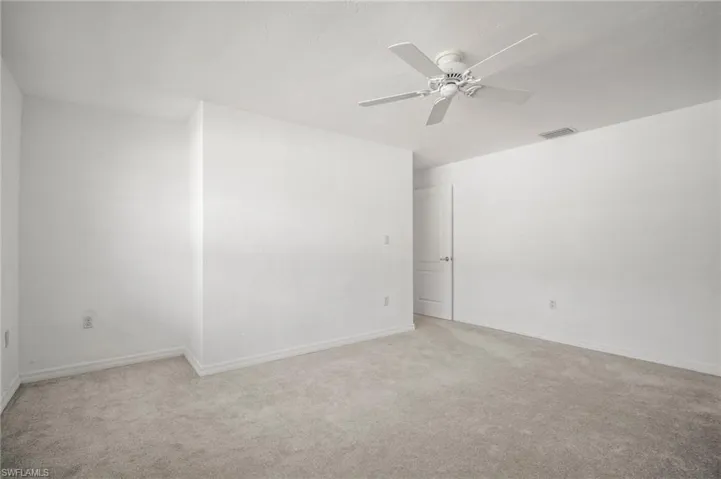 Empty room featuring visible vents, ceiling fan, light carpet, and baseboards