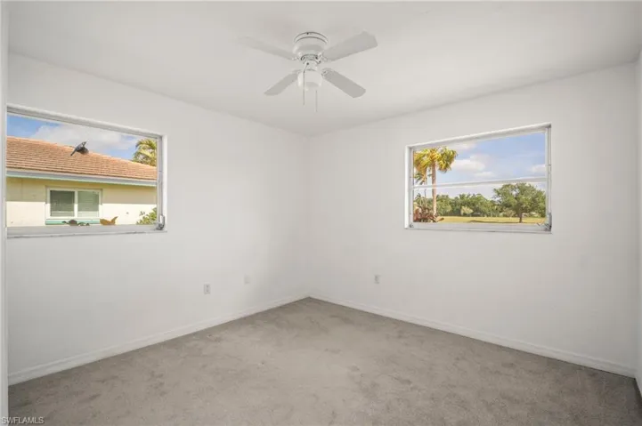 Empty room with ceiling fan, carpet floors, and baseboards